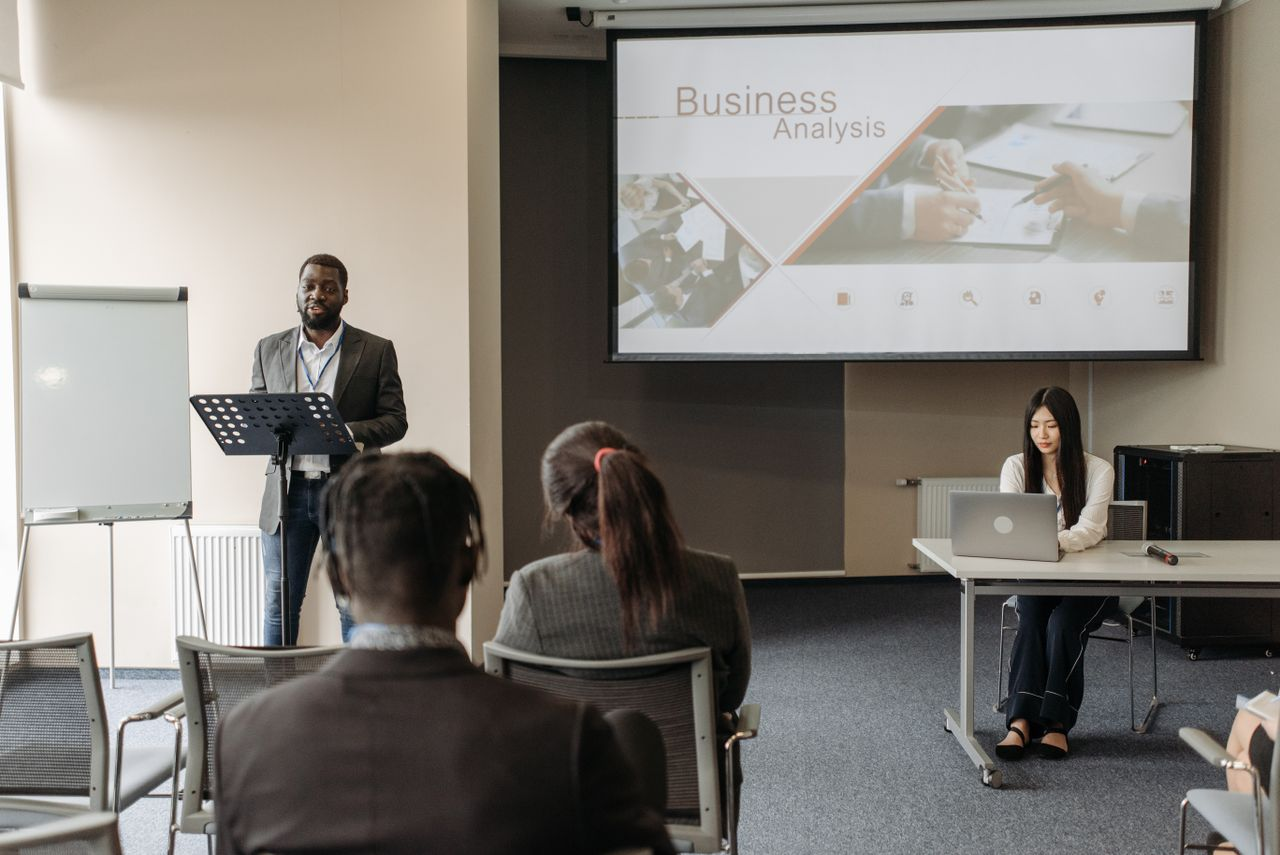 Business seminar with a speaker and audience in a conference room.